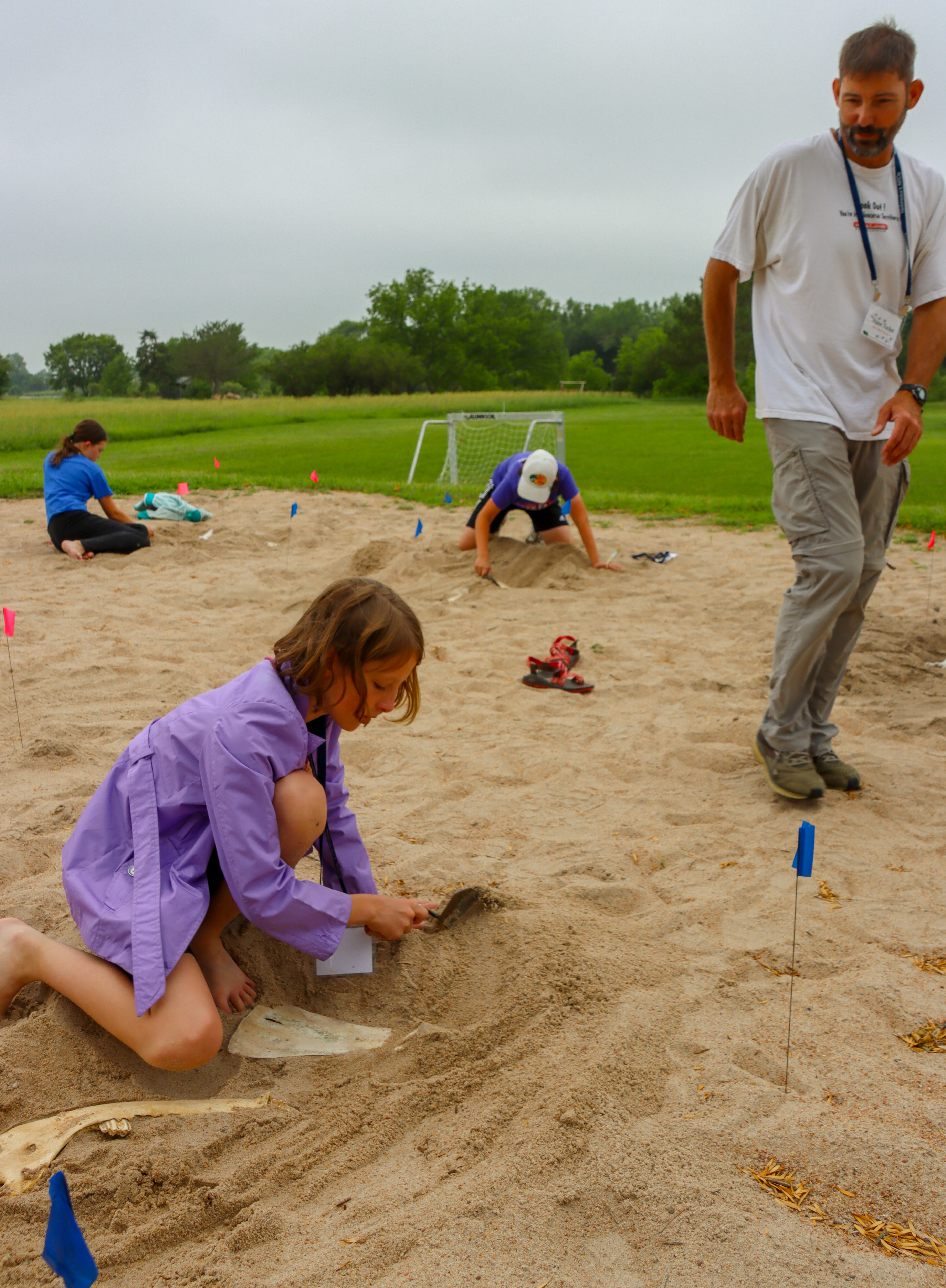 ACE Camp participants participate in the palentology educational session.  Shane Tucker, class instructor, observes students digging for fossils in the sand.