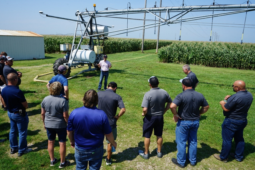 presenter speaking to group in a corn field