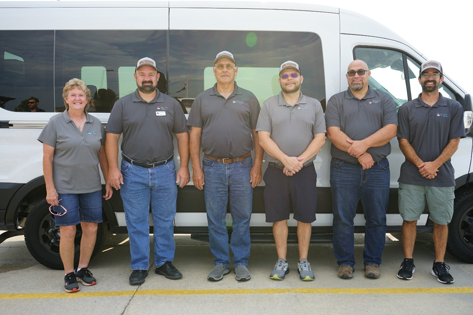 Directors posing in front of van