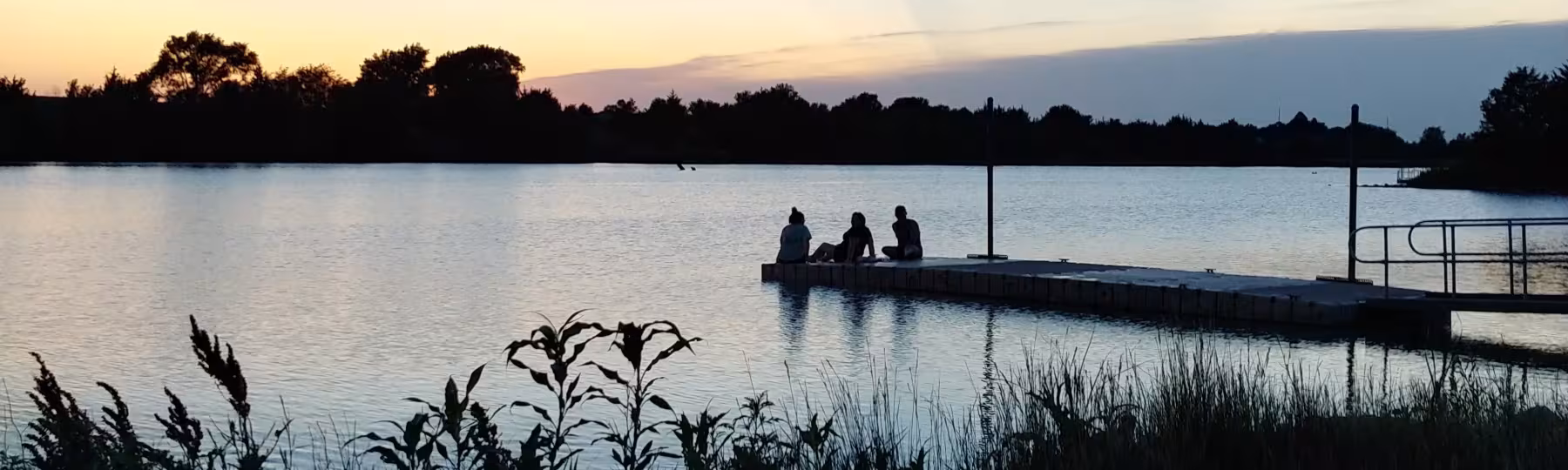 patrons sit on dock at Recharge Lake and watch sunset